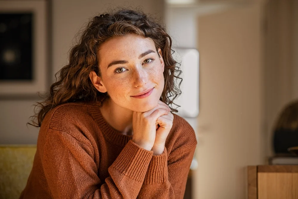 Young woman with a calm, confident expression, representing the comfort and clarity patients experience after a comprehensive eye exam at One EyeCare 